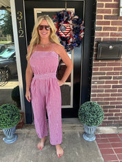 Woman in a pink checkered dress standing in front of a door with decorative wreath.