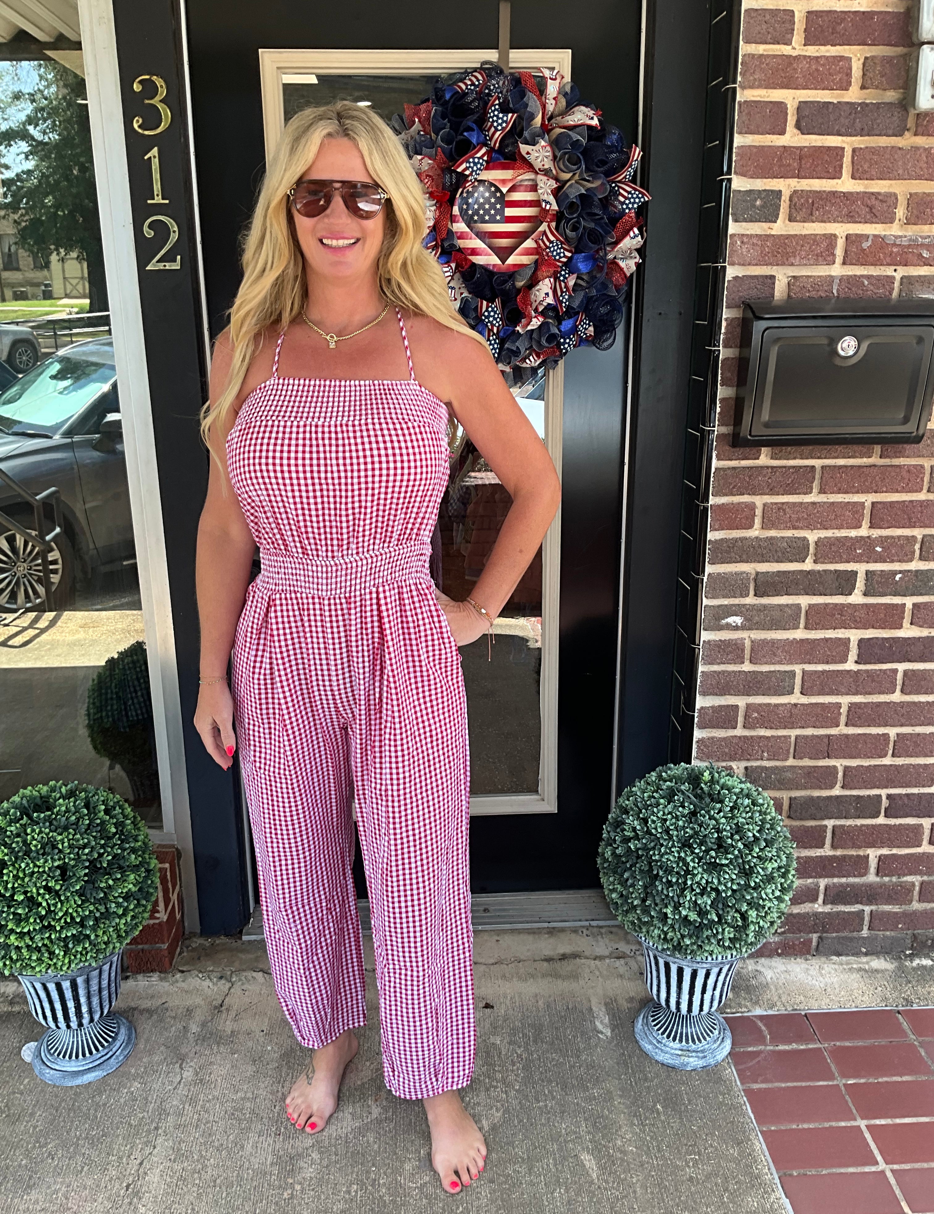 Woman in a pink checkered dress standing in front of a door with decorative wreath.