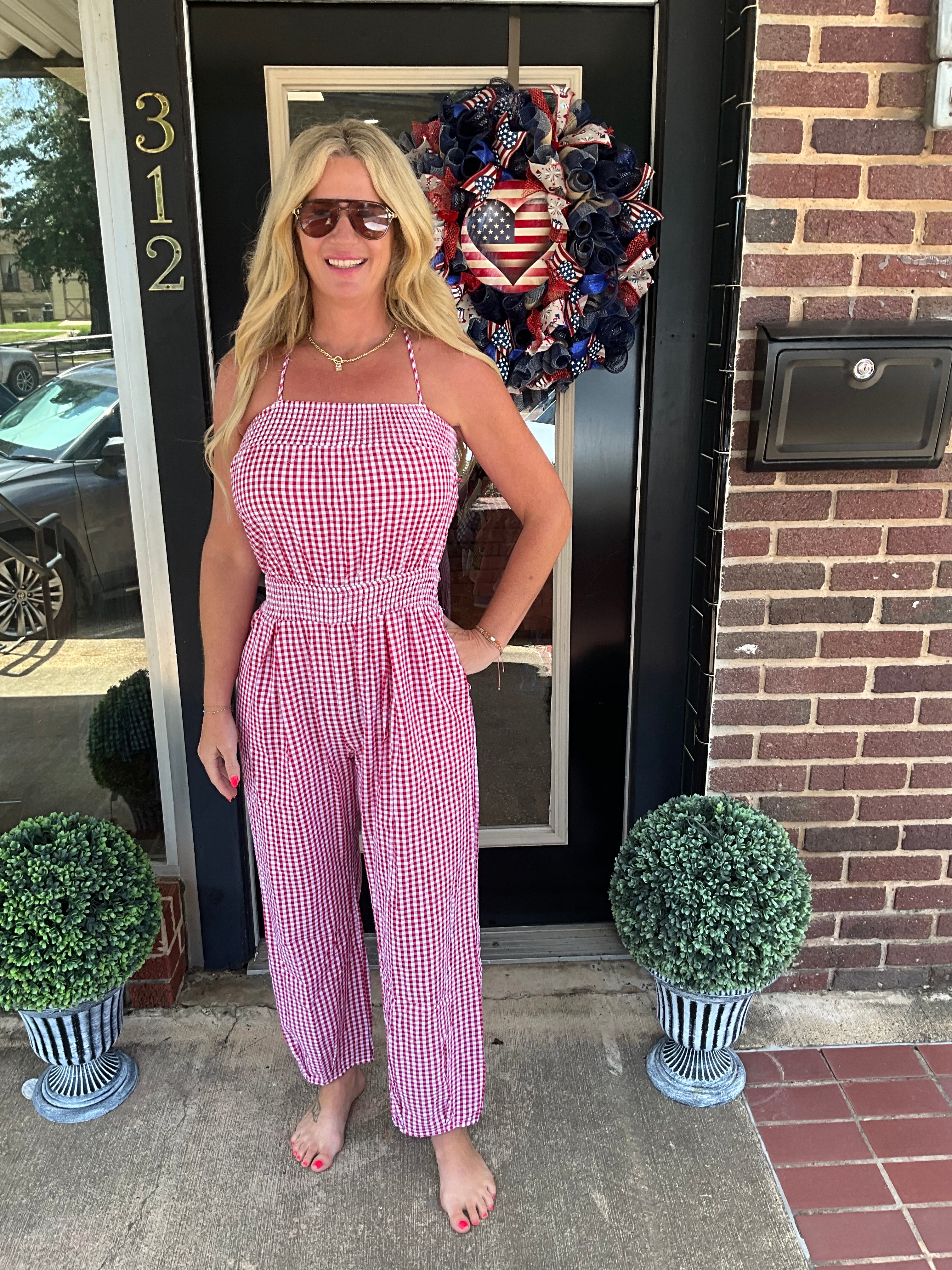 Woman in a pink checkered dress standing in front of a door with decorative wreath.